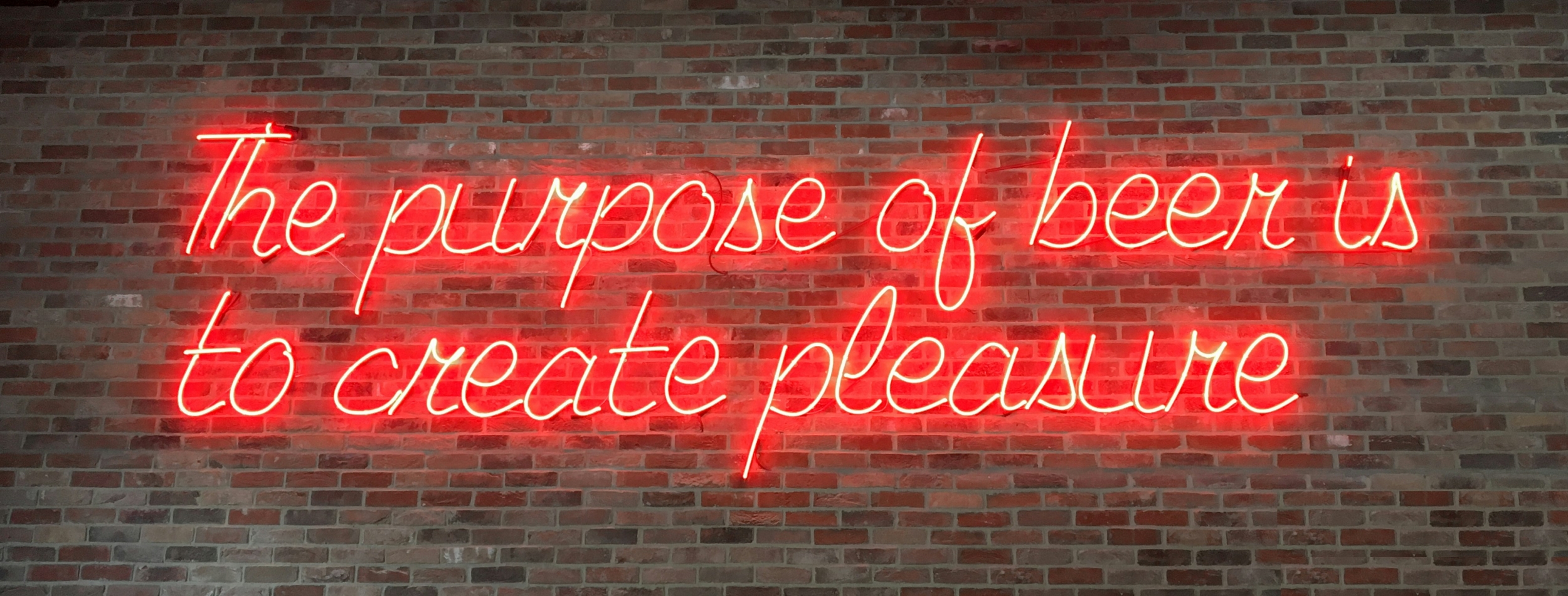 Neon sign that reads "The purpose of beer is to create pleasure"