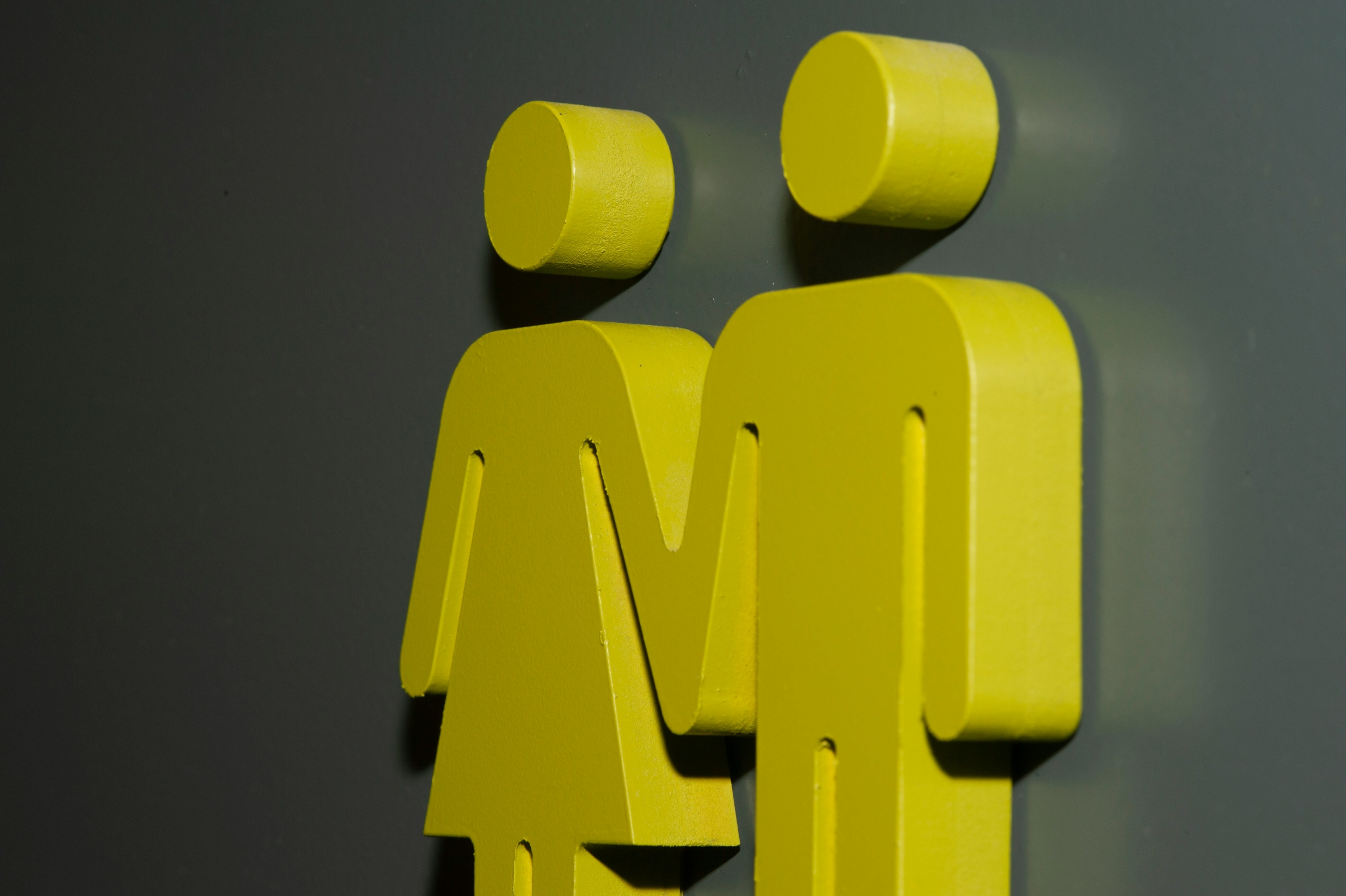 Yellow male and female icons on a concrete wall